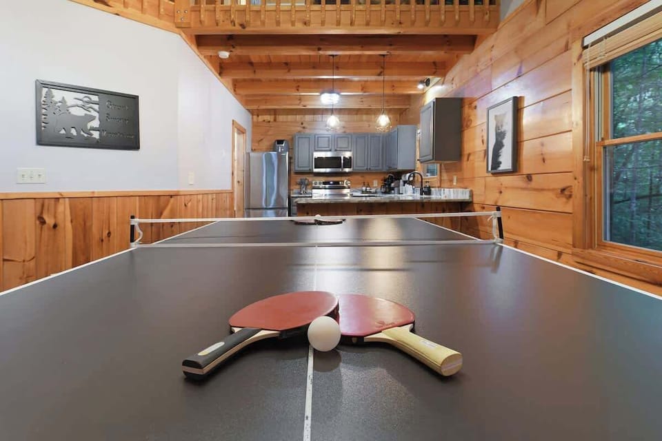 Rustic cabin interior featuring a ping pong table and a modern kitchen.