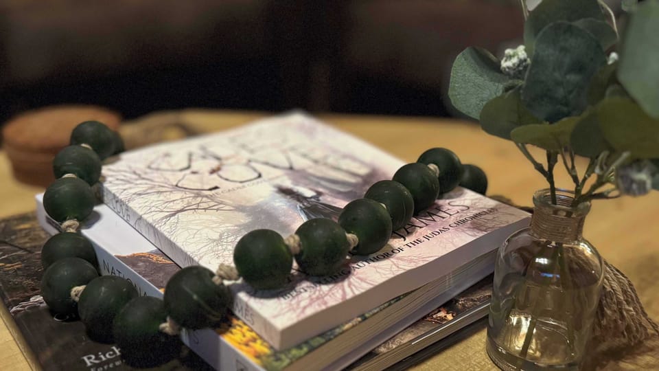 Close-up of decorative books and a glass vase with greenery on a wooden table.