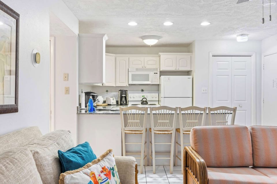 Bright kitchen with white cabinetry and a breakfast bar with seating for four.