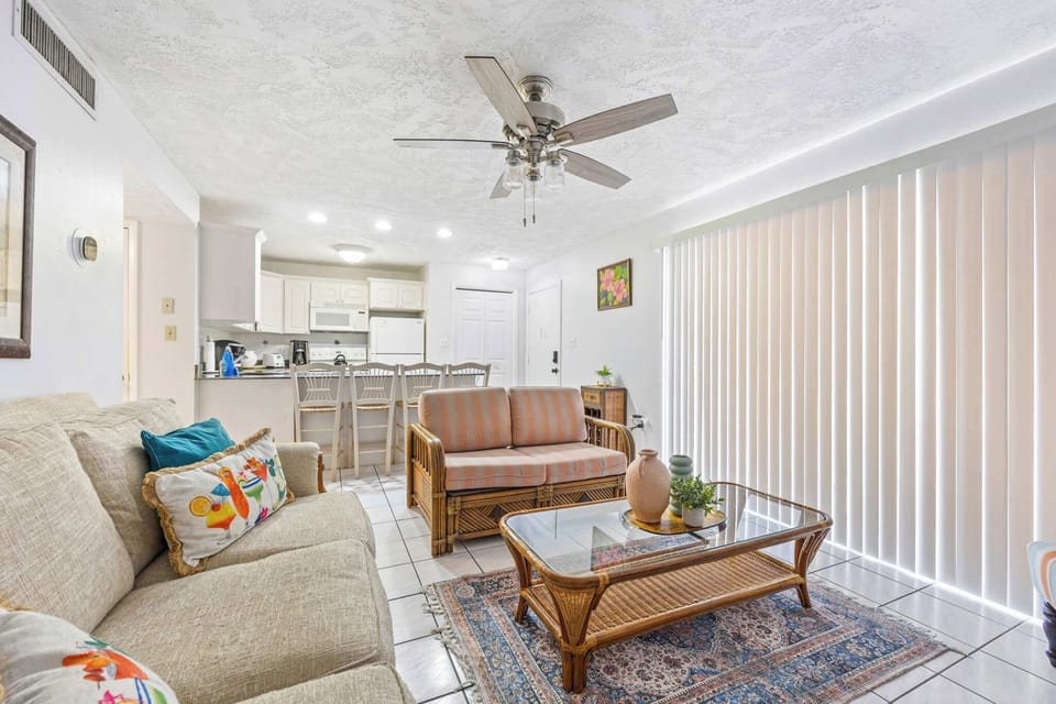 Bright living area with rattan furniture and a view into the kitchen.