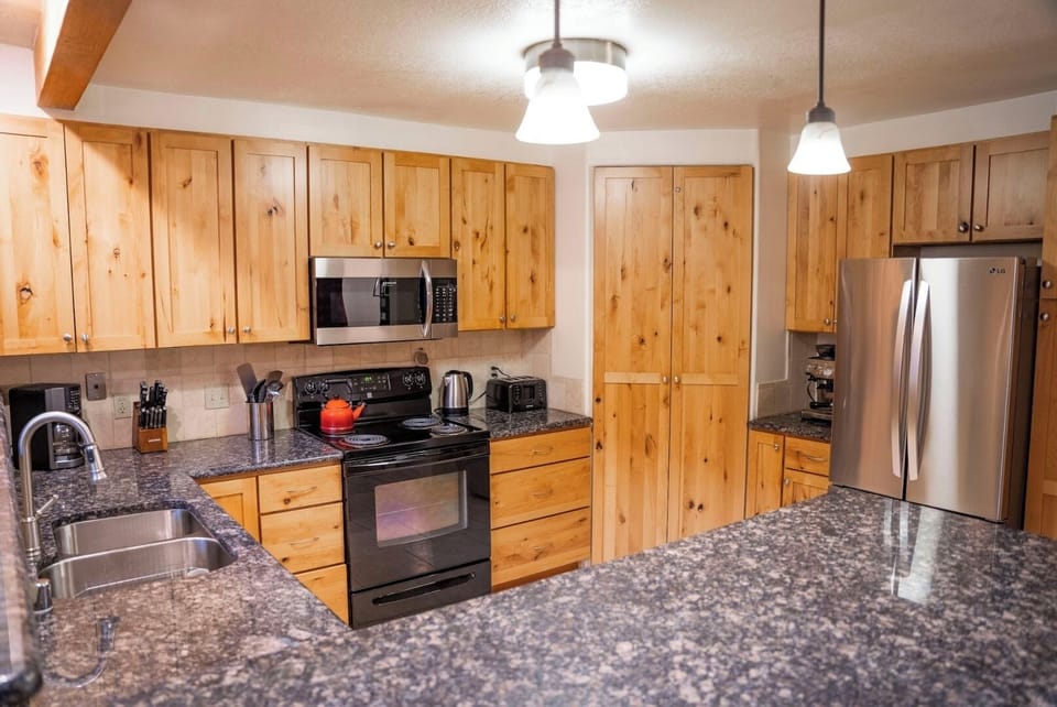Your spacious kitchen features warm pine cabinetry, sleek granite counters, and stainless steel appliances—perfect for preparing home-cooked meals during your mountain getaway.