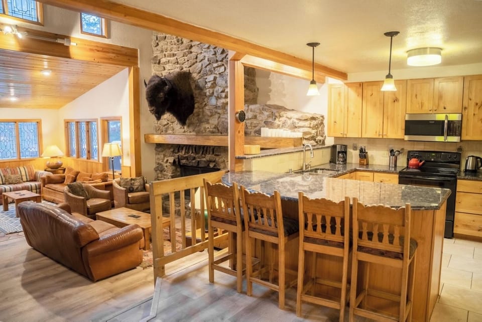 Picture yourself preparing meals together in this open-concept space, where rustic stone and warm wood create a welcoming mountain retreat. The full kitchen flows seamlessly into your living area, perfect for gathering.