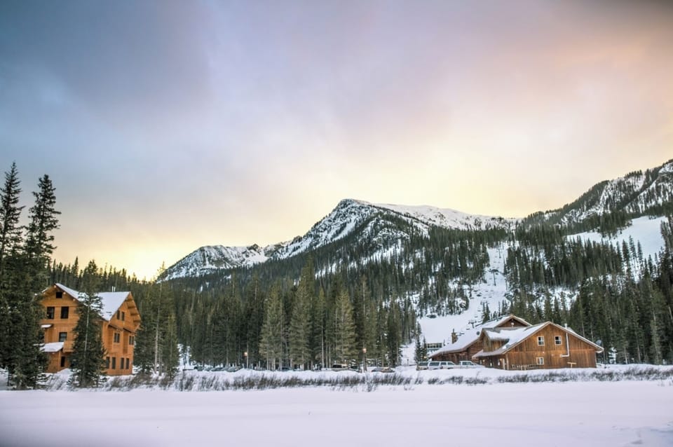 A snow-covered mountain retreat surrounded by evergreen forests and majestic peaks, offering a serene winter escape in the heart of nature.