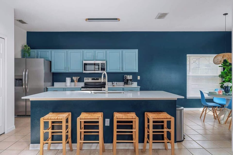 Bright and welcoming, this spacious kitchen features calming blue cabinetry and a sleek island with bar seating for four. Fully equipped with modern appliances and ample counter space, it's perfect for family meals or casual gatherings.