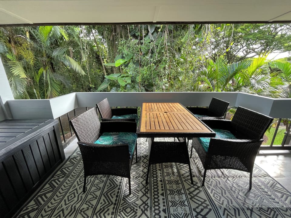 Large lanai under tall banyan tree, facing park/garden/pond with cool trade wind