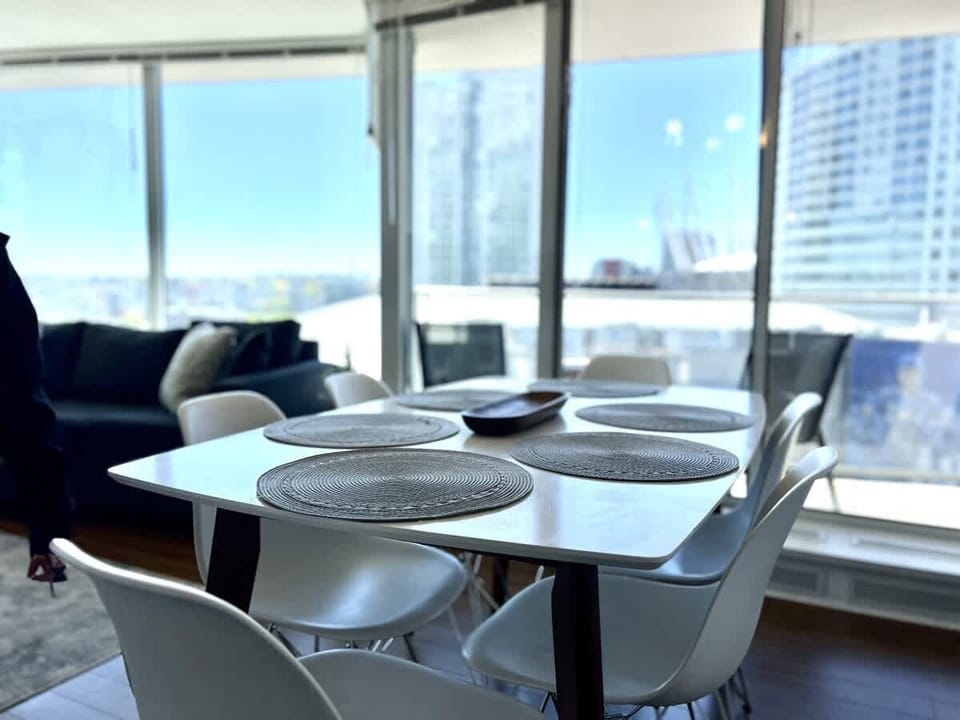 Share memorable meals and conversation at this bright dining table, surrounded by panoramic city views and the inviting warmth of your furnished Vancouver suite.