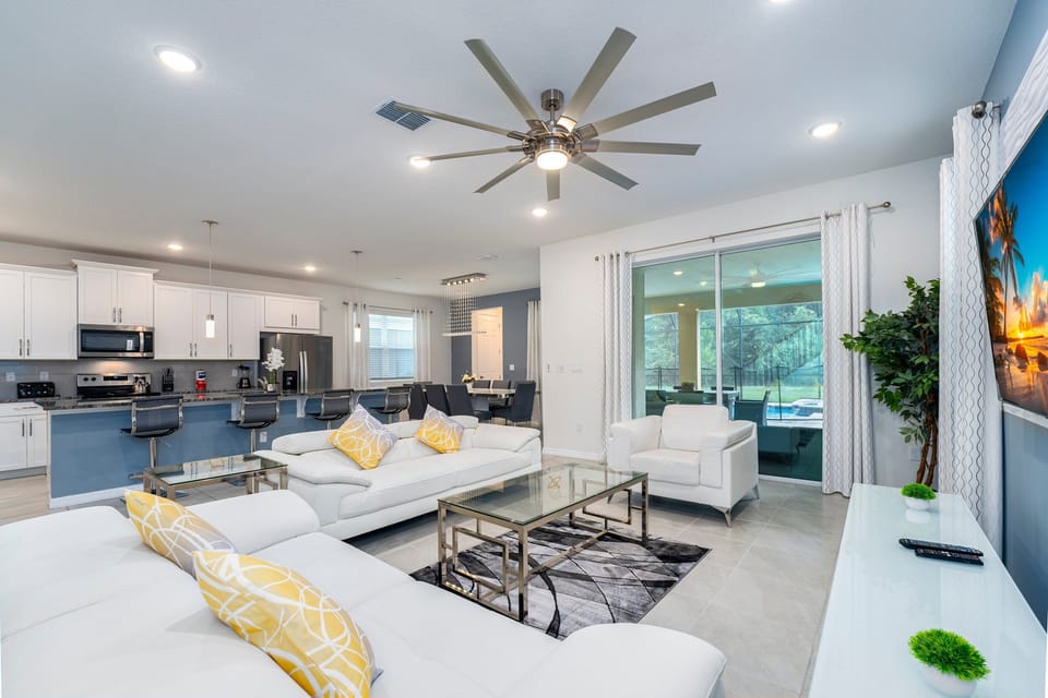 Modern living room with sleek furniture, bright decor, and open kitchen space.