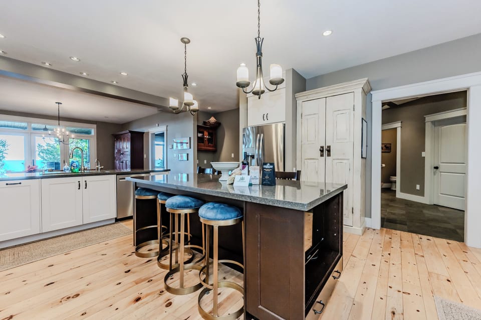 A luxurious kitchen island with bar seating, elegant light fixtures, and a view into the living room and outdoor space, ideal for entertaining and casual dining.