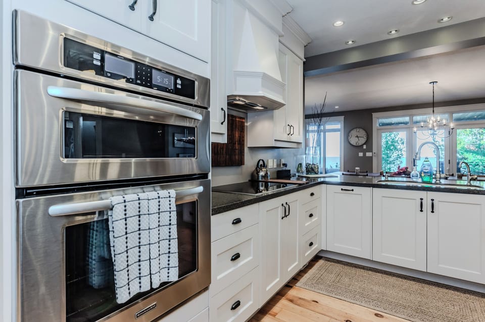 Sleek kitchen featuring stainless steel appliances, custom white cabinetry, and a spacious countertop—combining functionality with style in a bright, open space.