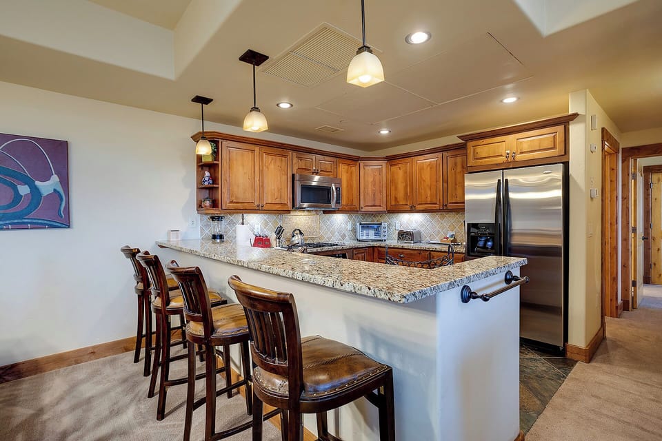 Your fully equipped kitchen awaits with granite counters, stainless appliances, and a breakfast bar perfect for morning coffee or casual meals together.
