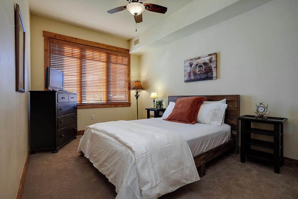 Sink into crisp linens in your cozy bedroom, where rustic charm meets modern comfort with a ceiling fan and peaceful mountain views.