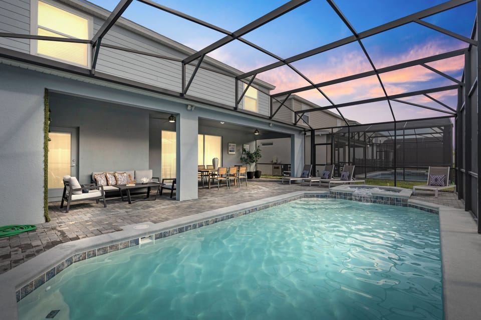 Discover a serene oasis with a sparkling pool, stylish stone tiles, and comfortable lounge chairs. The spacious area, enclosed for your comfort, beckons you to unwind as the sunset fills the space with a warm glow.