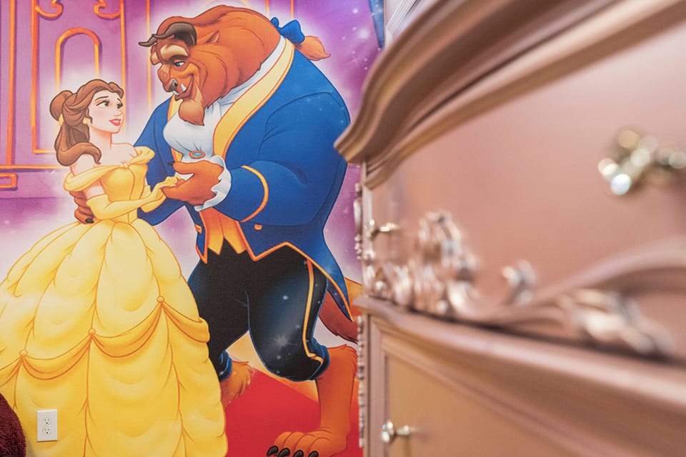 Enter a whimsical world of charm and comfort, highlighted by a stunning mural of classic characters. The soft pink furniture enhances the vibrant artwork, creating a delightful atmosphere ideal for your relaxation.