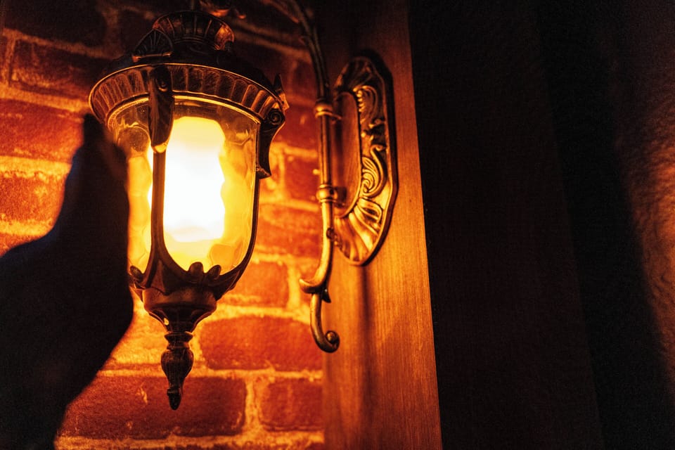 Experience a cozy ambiance where a vintage lantern casts a soft glow on a rustic brick wall, creating a warm, inviting atmosphere perfect for you to relax and unwind in.