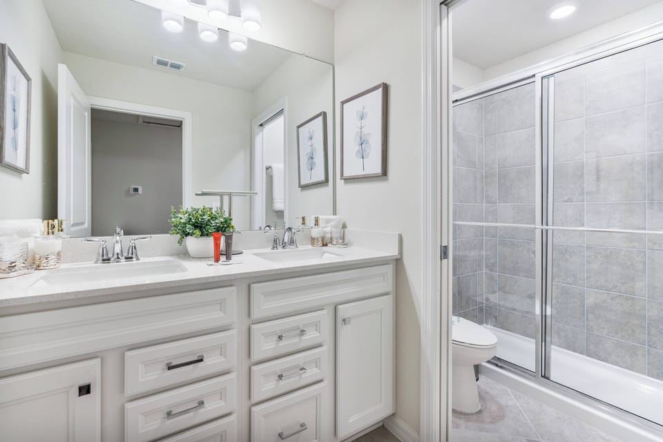 Enjoy a spacious double vanity with sleek cabinetry and modern fixtures in this well-appointed bathroom. The luxurious large glass shower and soft lighting provide a bright, refreshing atmosphere for your stay.