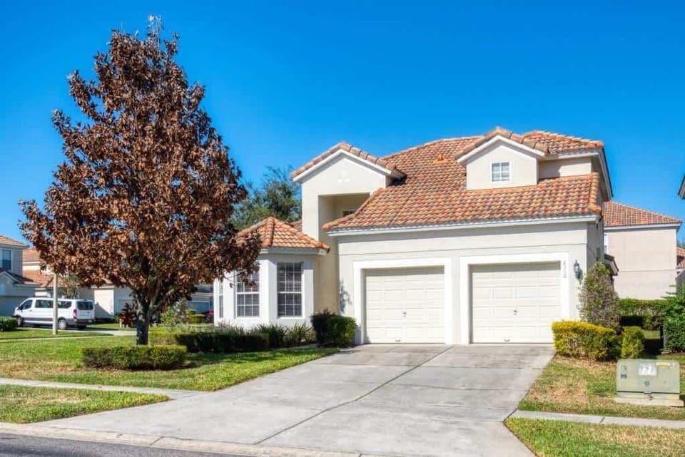 This image features a charming two-story suburban home with a red-tiled roof and a double garage.