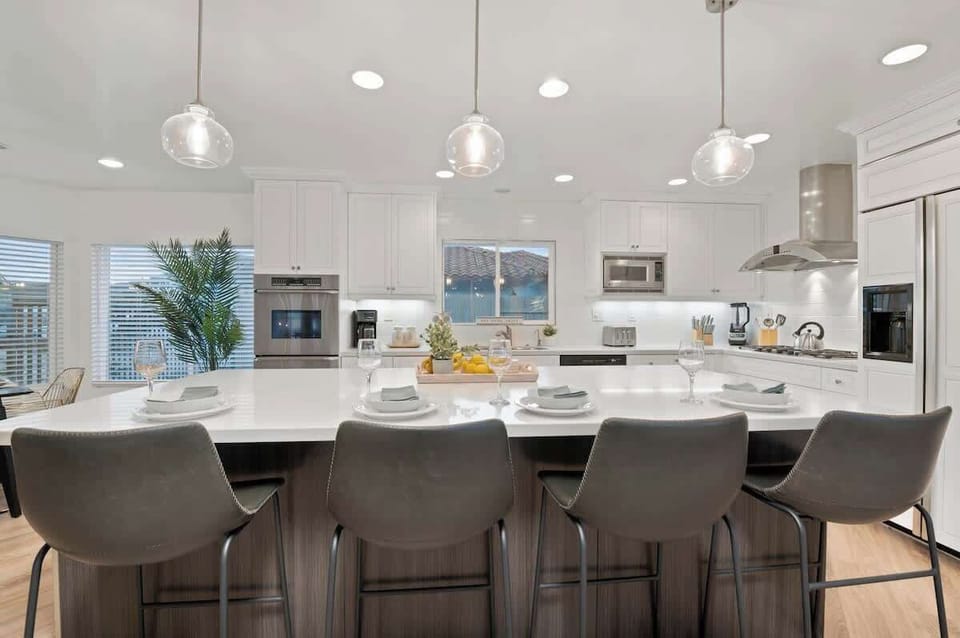 With a modern white design and sleek island counter, this kitchen is fully equipped with built-in appliances and offers cozy chairs for casual meals. The ample space is perfect for effortless meal prep and entertaining.