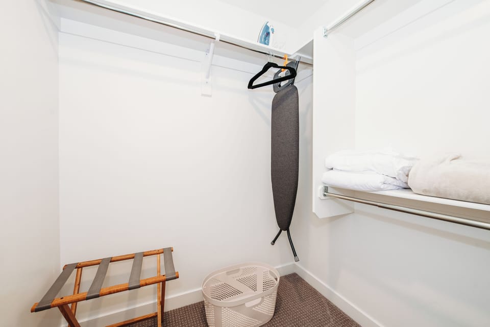 Closets stocked with ironing board, racks, and extra linens.