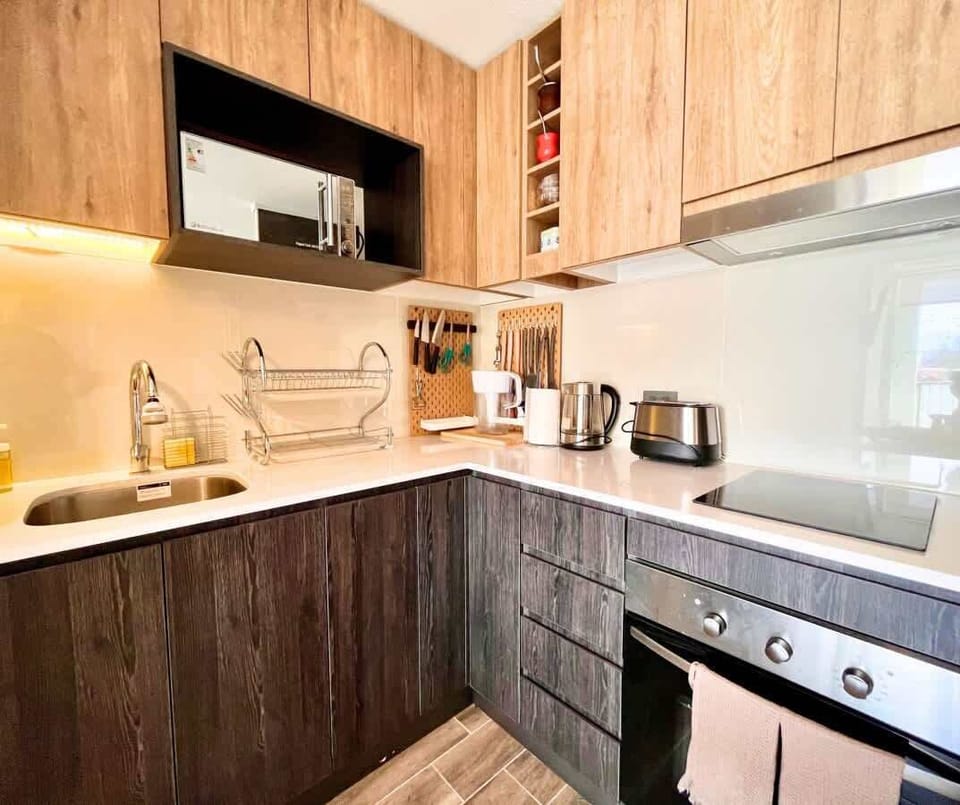 Compact kitchenette w/ wood cabinets, stove & open shelving.