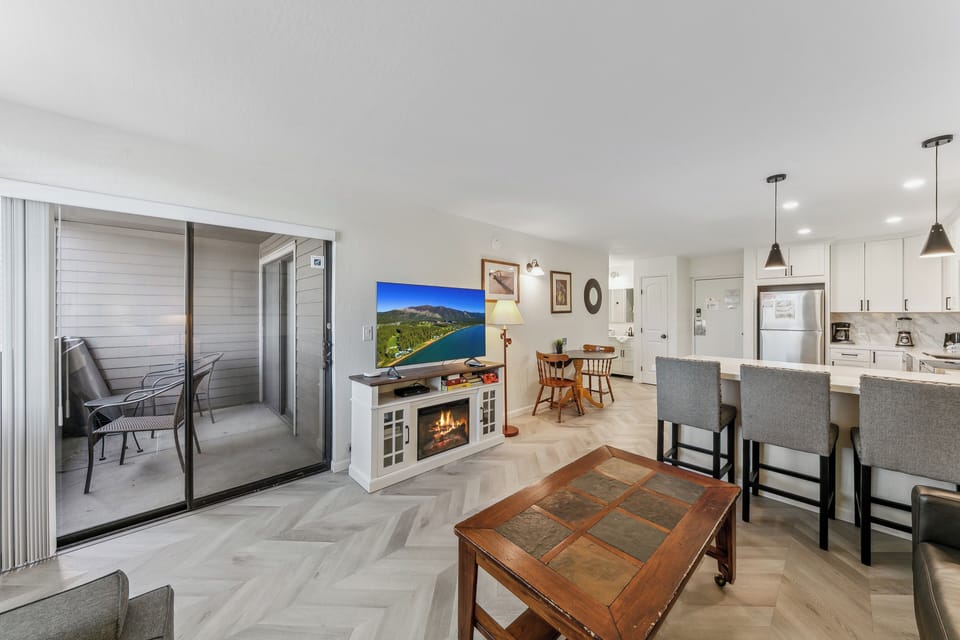 Your spacious open-plan retreat seamlessly blends kitchen, living, and dining areas with cozy fireplace warmth and private balcony access.