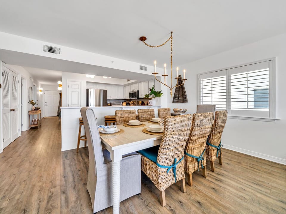 Gather around your elegant dining table with wicker chairs, where coastal style meets comfort under ambient lighting for memorable meals together.