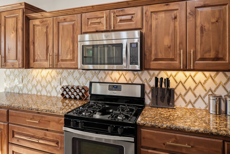 Lighted marble backsplash pulls the well-stocked kitchen together.