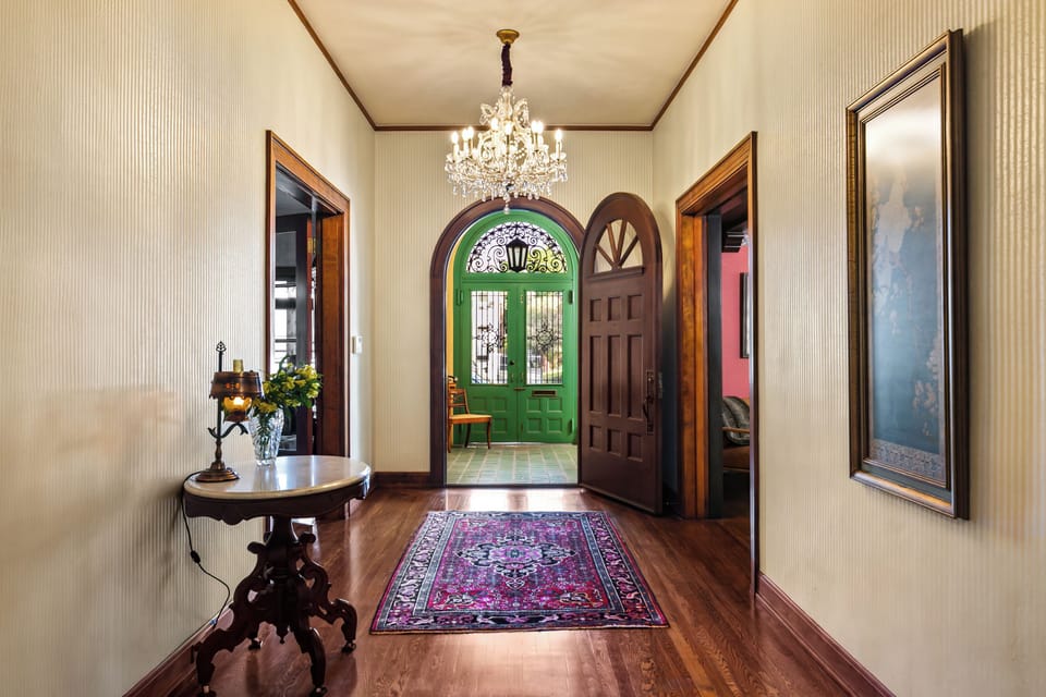Elegant foyer with chandelier and arched entry door.