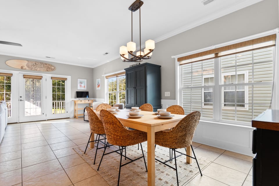Your bright dining area features a warm wood table and woven chairs under elegant pendant lighting, perfect for memorable meals.