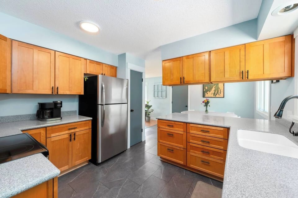 Large kitchen with all the basic necessities, including a keurig with individual or full pot options, salt, pepper, olive oil spray, pots, pans, glassware, plasticware, dining ware, utensils, and a dishwasher.