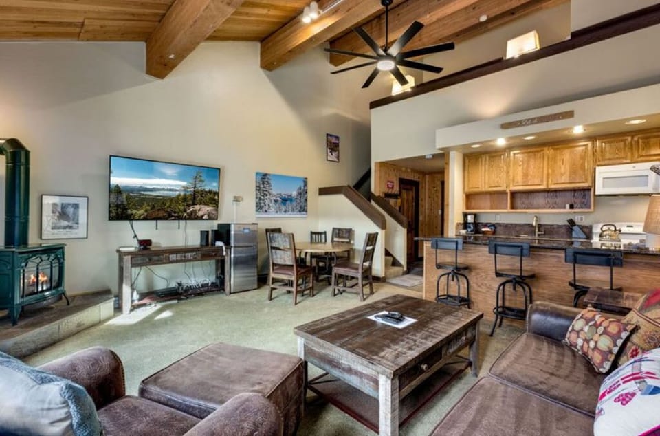 Enjoy the open-plan living room, showcasing rustic wooden beams, ample seating, and a flat-screen TV.