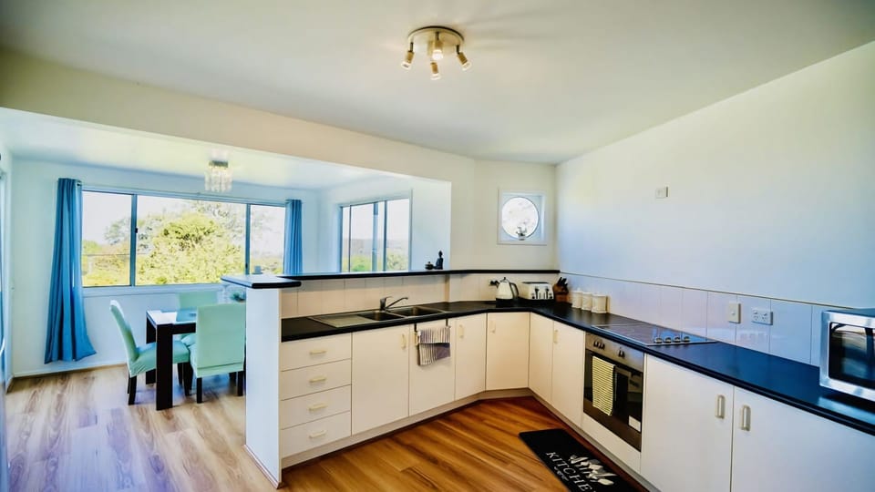 L-Shaped Benchtop: The kitchen features a clean, L-shaped layout with white cabinetry and dark countertops, maximizing the workspace.