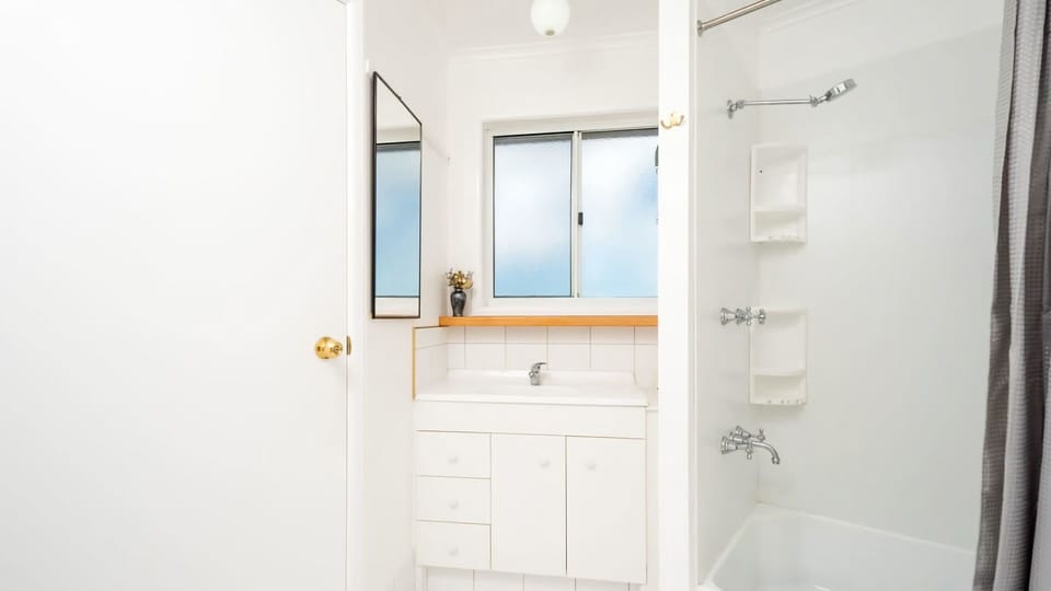 Our bright, clean bathroom features a convenient shower/tub combination, a vanity with storage, and a large mirror.