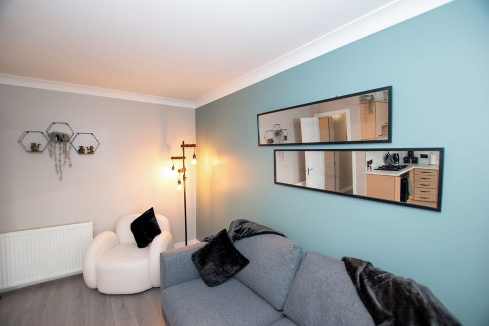 Modern living room with a 55" wall-hung TV, stylish double sofa bed, and boucle armchairs. Wood-pane (4)
