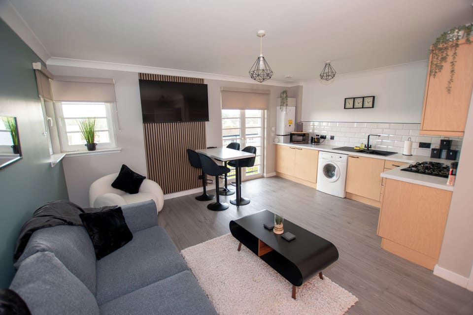 Chic open-plan breakfast bar with velvet stools leads to a fully equipped modern kitchen, stocked fo