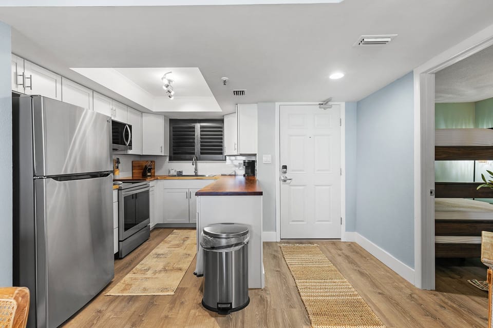 A sleek, contemporary kitchen featuring stainless steel appliances, white cabinetry, wood countertops, and rustic accents. The open design provides a spacious feel, perfect for cozy living or entertaining.