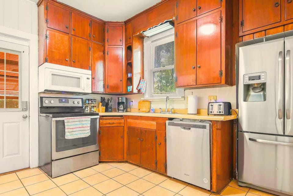 A well-coming fully stocked kitchen w/ orange cabinetry and modern appliances