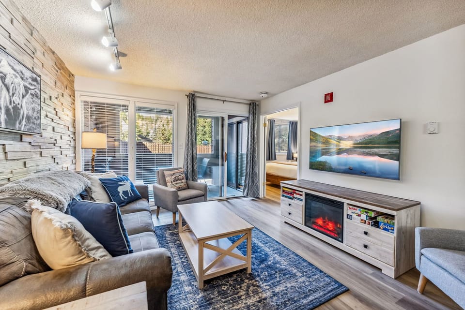 Living Room: Couch w/pull out bed, 2 chairs, gas fireplace, 55” TV, entertainment center w/electric fireplace, access to a private balcony
