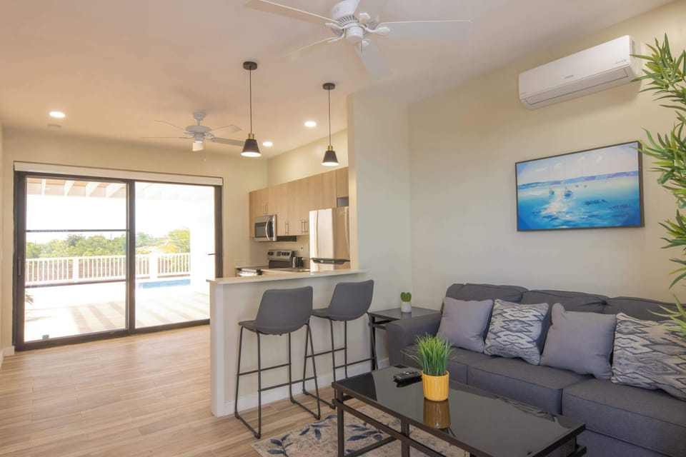 Modern open-plan living with kitchen, breakfast bar, and pool deck access