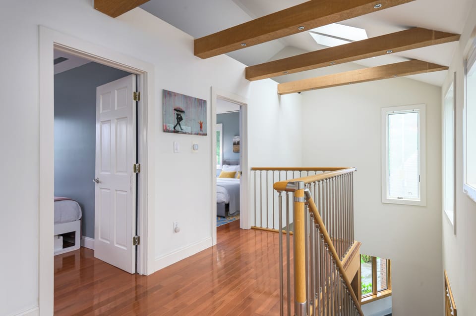 Bathed in natural light, the upstairs hallway leads to two cozy bedrooms and a shared bathroom - quiet, bright, and tucked away.