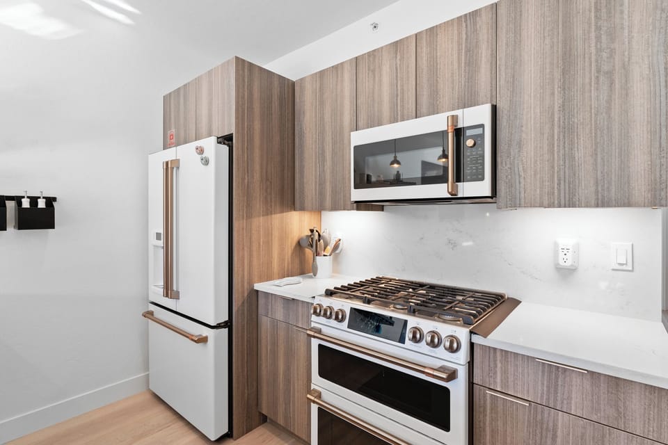 Your modern kitchen features sleek wood-grain cabinetry, quartz countertops, and premium stainless steel appliances for effortless home-style cooking.