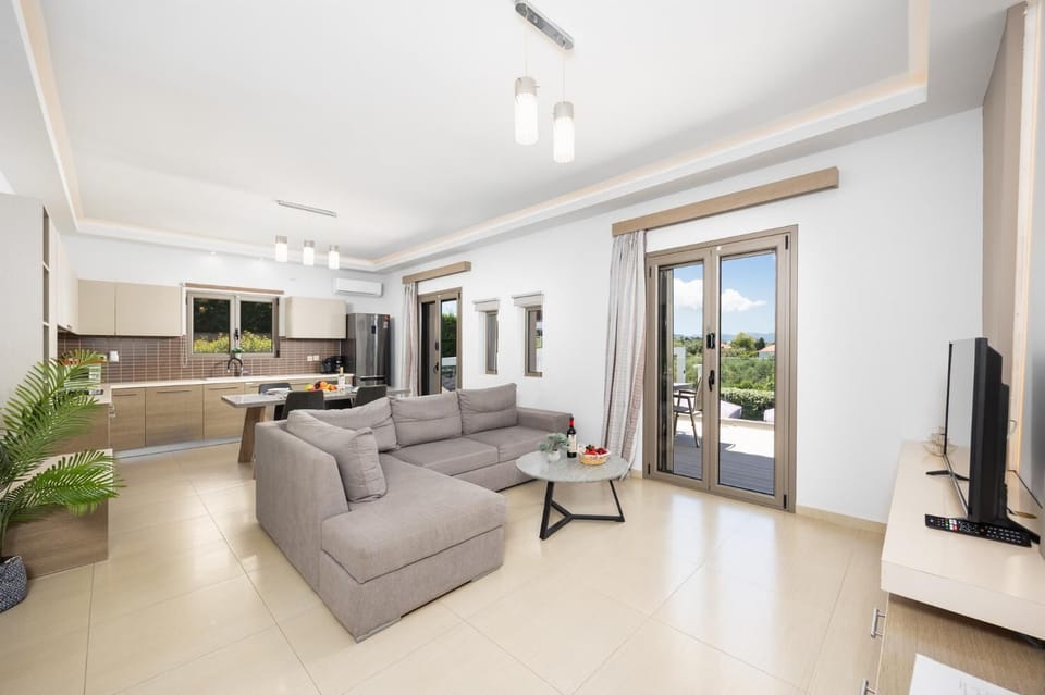 Open-plan living room with sofa, dining area, kitchen, A/C, WiFi internet, and satellite TV