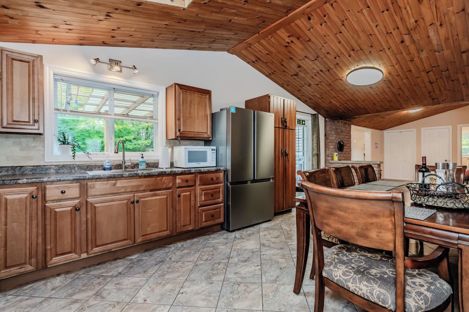 Cook with ease in this modern kitchen that offers plenty of counter space, stainless steel appliances, and views of the outdoor greenery.