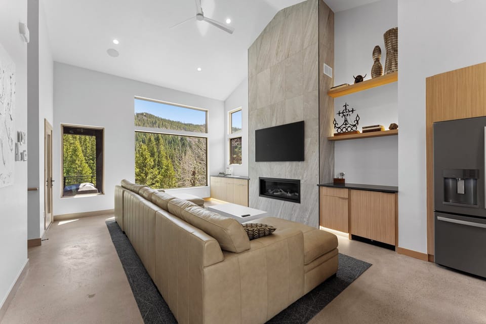 Top floor living area with ample seating, fireplace, dry bar with wine fridge, and large windows with stunning views.