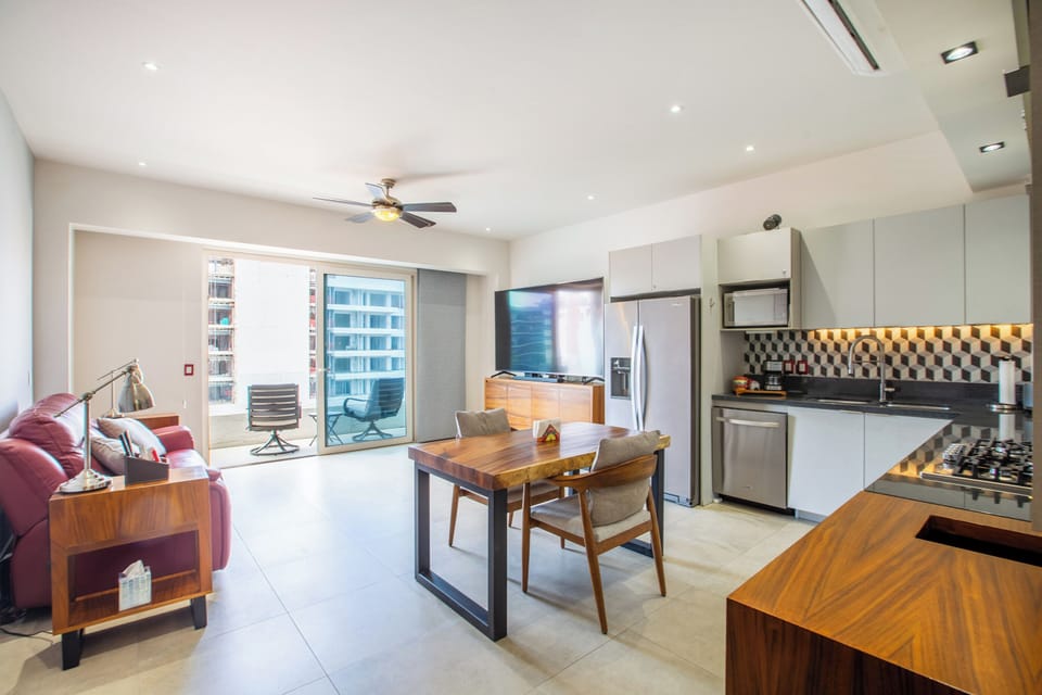 Open-concept living area with a sleek kitchen and balcony with outdoor seating