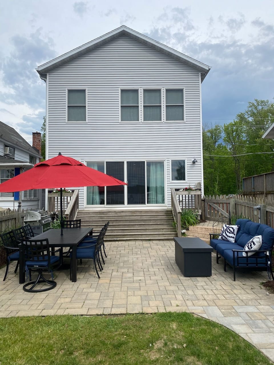Cozy outdoor living with large dining table, grill, firepit table, and hot tub.