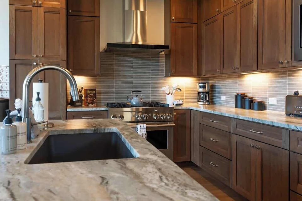 This chef’s kitchen features rich wood cabinetry, sleek stone countertops, and high-end appliances—perfect for creating meals to match the view.