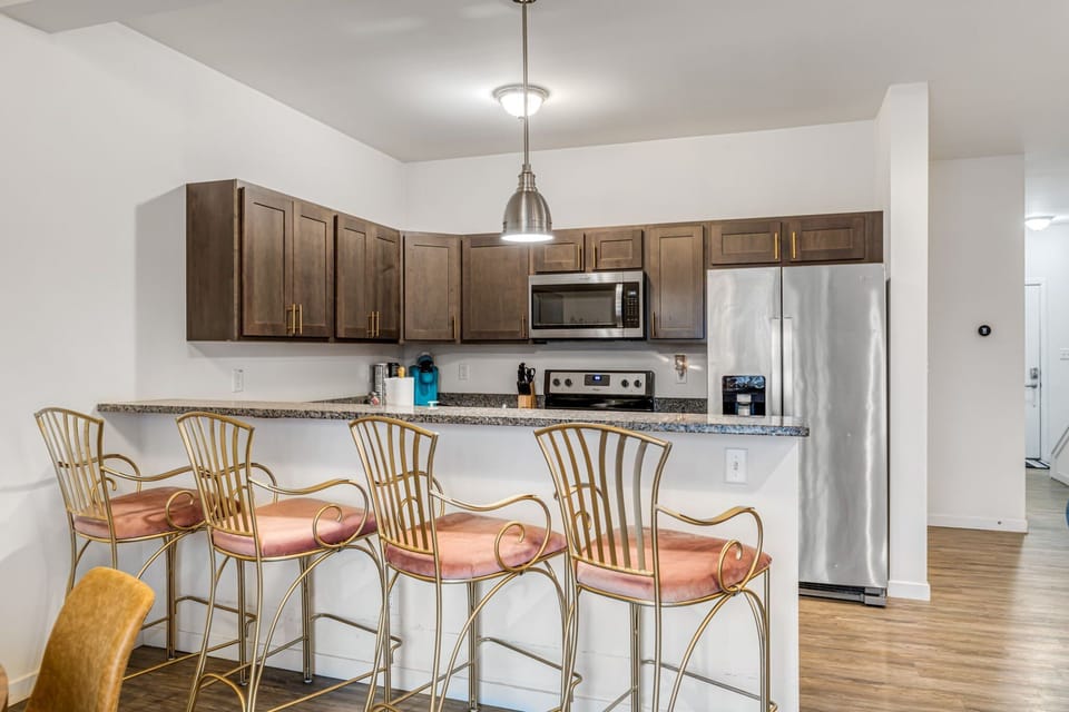 The spacious kitchen includes stainless appliances, generous cabinetry, stone counters, and a four-seat breakfast bar.