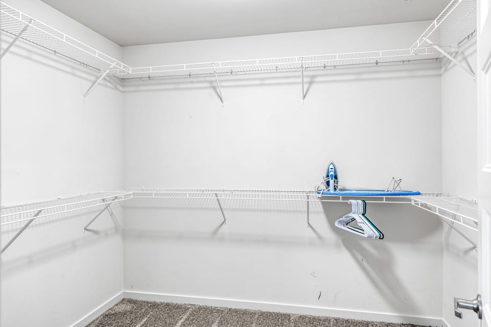 A large walk-in closet provides wraparound hanging rails, shelves, and an ironing board for guest use.