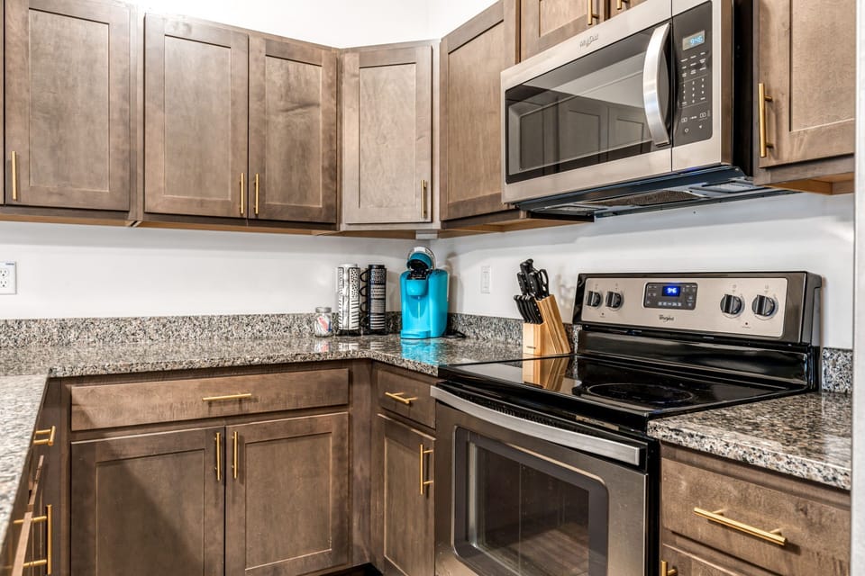 The cooking area includes a stainless range and microwave, substantial cabinet storage, and generous counter space.