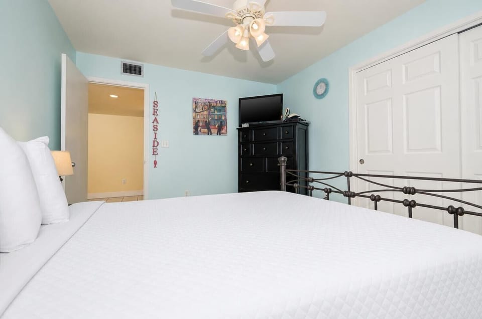 This guest bedroom features a stylish black dresser, a flat-screen TV, and cheerful seaside decor, perfect for relaxation